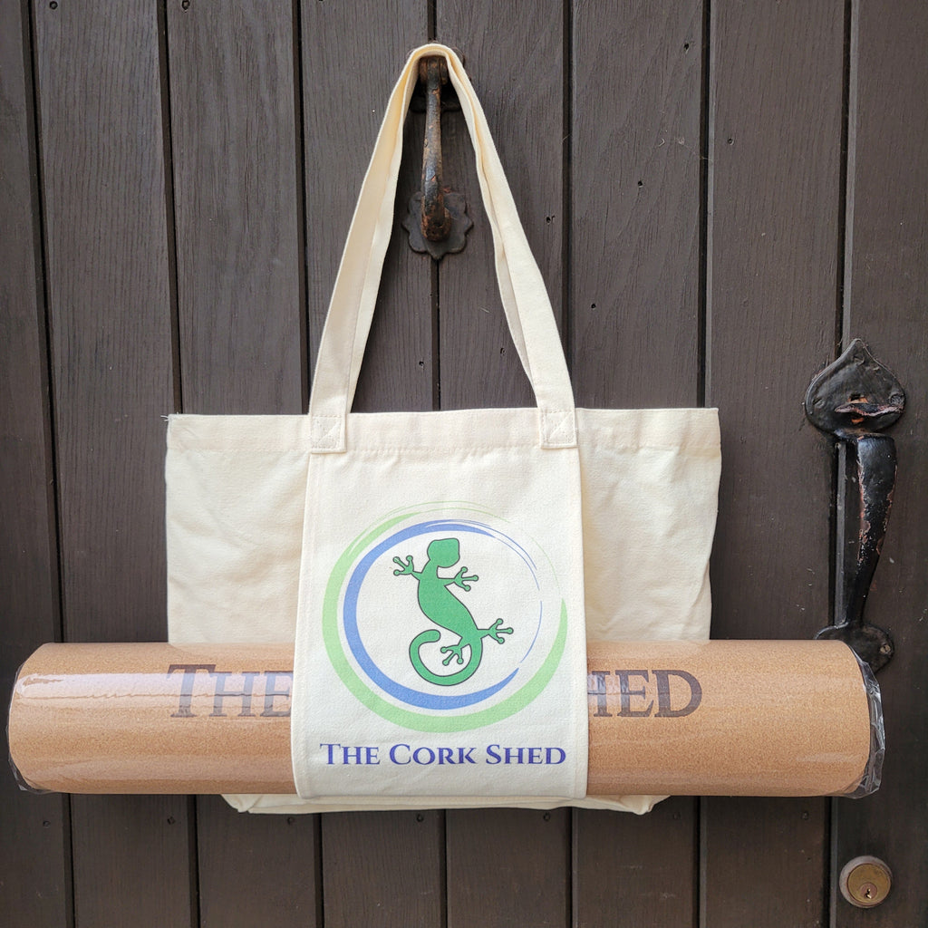 Canvas tote bag with rolled-up cork board and 'The Cork Shed' branding on a wooden surface.